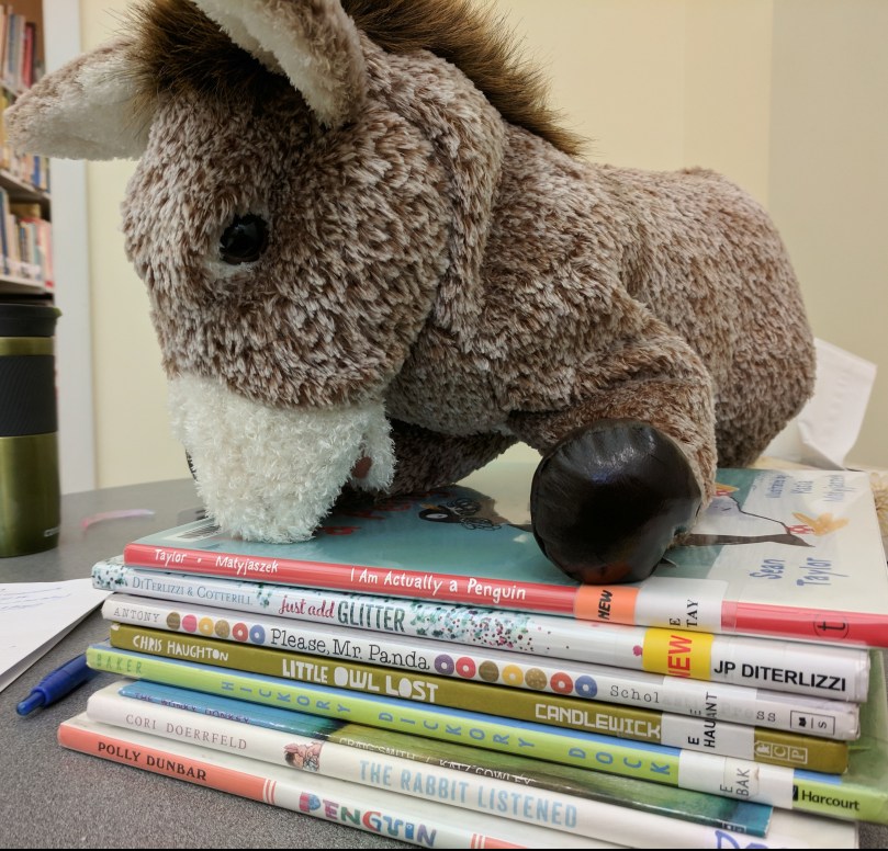 Donkey puppet atop stack of picture books