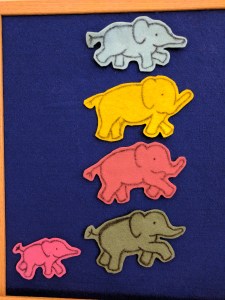 Blue, yellow, red, and green felt elephants on felt board