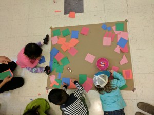 Bird's-eye view of kids gluing squares to paper