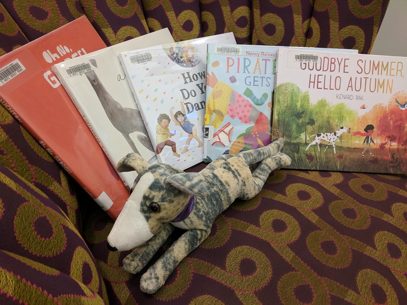 Picture books cover out on chair with greyhound stuffed animal