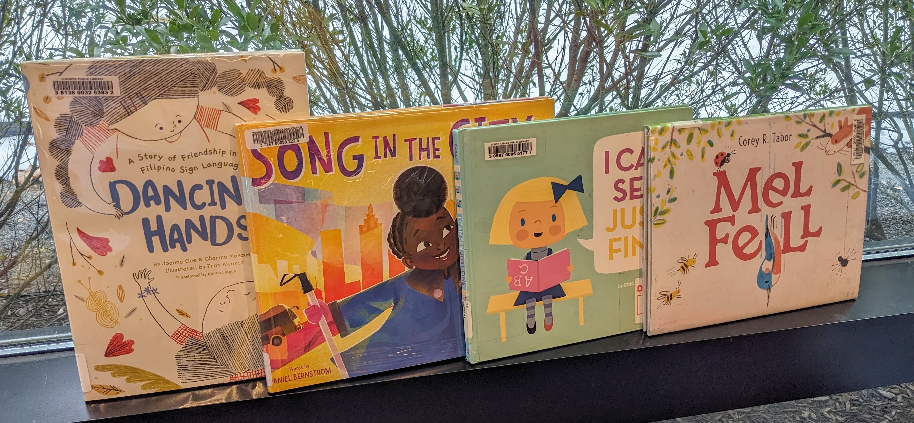 Books on window ledge: Dancing Hands, Song in the City, I Can See Just Fine, and Mel Fell