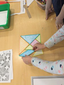Hands arranging tangrams on a table